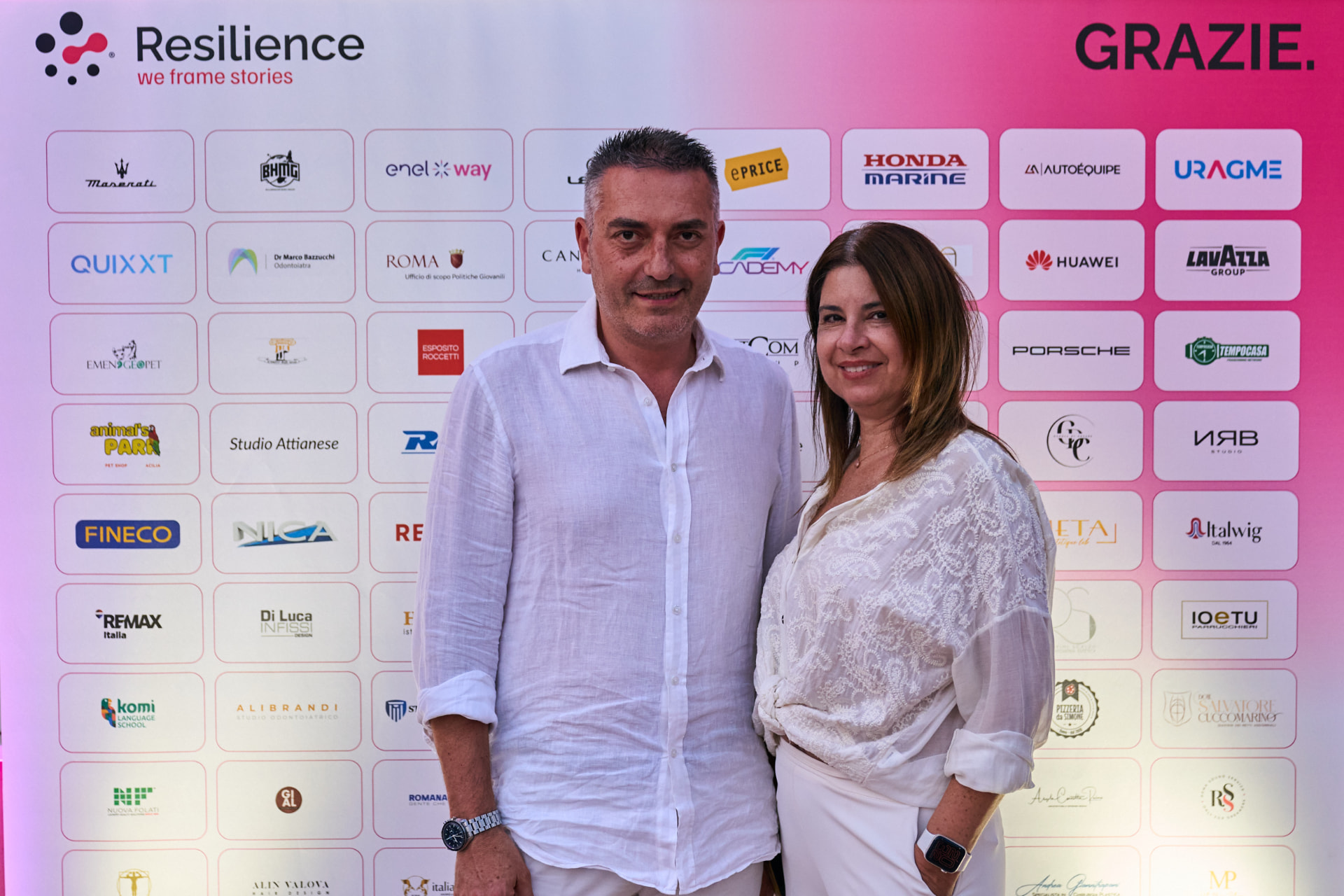 Ospiti davanti al photo wall Resilience con i loghi dei partner